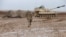 FILE - A U.S. soldier walks in front of a tank at an army base in Karamless town, east of Mosul, Iraq, Dec. 25, 2016. 