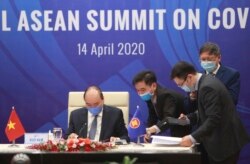 FILE - Vietnamese Prime Minister Nguyen Xuan Phuc, left, and his staff prepare documents ahead of the Special ASEAN summit on COVID-19 in Hanoi, April 14, 2020.
