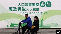 A man and woman ride an electric bicycle past a publicity board China's census in Beijing, 1 Nov. 2010. China kicked off its once-a-decade census on Monday, a whirlwind 10-day head count.