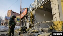 Fuerzas militares rusas inspeccionan los daños a una tienda seriamente dañada durante un bombardeo en la región ucrania de Donetsk, ocupada por Rusia, el 19 de febrero de 2023. 