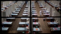 FILE - A hospital staff walks past rows of beds at a makeshift COVID-19 care center at an indoor sports stadium in New Delhi, India, July 8, 2020.
