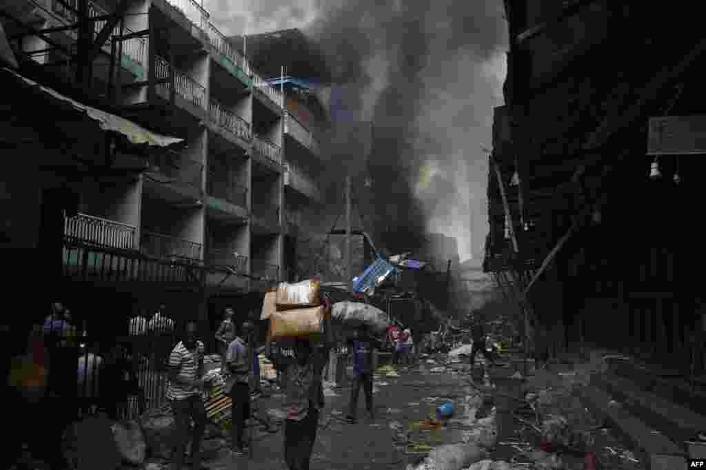 People carry goods salvaged from a fire that broke out in a section of the Balogun market in Lagos, Nigeria.