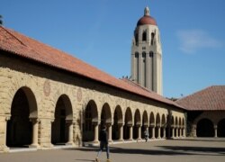 FILE- People walk on the Stanford University campus beneath Hoover Tower in Stanford, Calif., March 14, 2019.