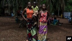 Monique Moukidje, 34 ans, à gauche, avec ses deux enfants Marienne et Odalvia, à Mbangui-Ngoro, le village centrafricain où elle et des centaines d'autres personnes déplacées qui ont fui Bangassou ont trouvé refuge, le 15 février 2021.