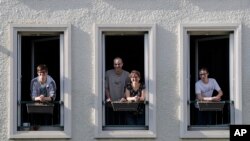 In this photo taken April 16, 2020, Jerome, second left, Nadege and their children Thomas, 17, left, and Pierre, 14, both with intellectual disabilities pose at the window of their apartment in Montigny-le-Bretonneux, near Paris. 