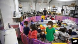 FILE - Unaccompanied migrant children, from ages 3 to 9, watch television inside a playpen at the U.S. Customs and Border Protection facility in the Rio Grande Valley in Donna, Texas, March 30, 2021.