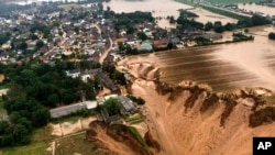 Rescuers rush to help people trapped in their homes in the town of Erftstadt, southwest of Cologne. Aerial pictures, like this one provided by the Cologne district government, show what appears to be a massive sinkhole.