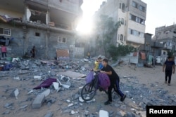 Pemuda Palestina berjalan di depan sebuah bangunan yang rusak pasca serangan Israel, di Khan Younis di selatan Jalur Gaza, 30 Oktober 2023. (Foto: REUTERS/Mohammed Salem)