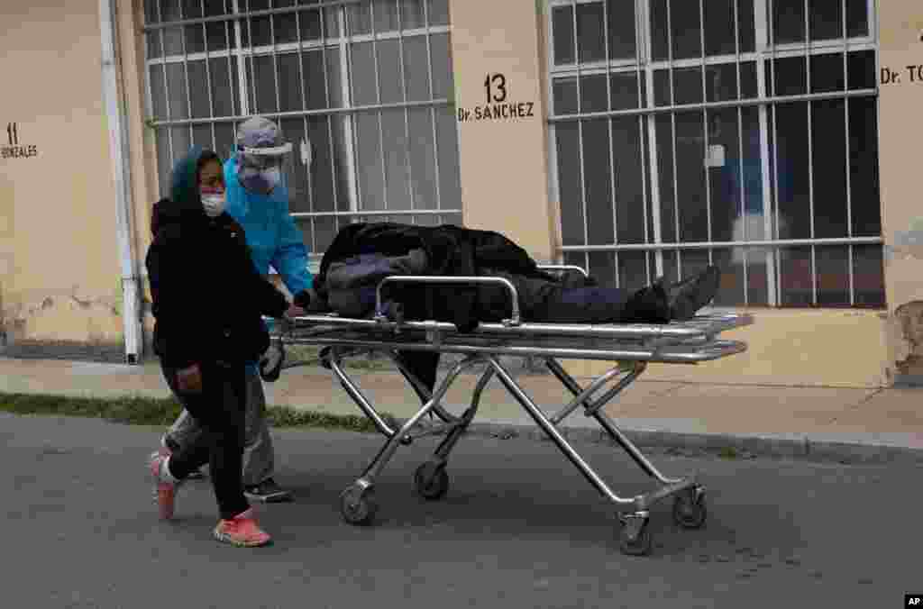 A health care worker dressed in protective gear pushes the body of a man who died of COVID-19, on a stretcher outside the General Hospital in La Paz, Bolivia.