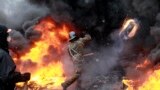 A pro-European protester throws a burning tire during clashes with riot policemen in Kyiv. The European Union threatened to take action against Ukraine over its handling of anti-government protests after three people died during violent clashes in the capital.