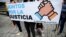La gente sostiene una pancarta que dice "Juntos por la justicia" durante una protesta contra el gobierno del presidente venezolano Nicolás Maduro antes de la llegada al país del Fiscal de la Corte Penal Internacional, Karim Khan, en Caracas, el 29 de octubre de 2021.