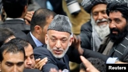 ປະທາທິບໍດີອັຟການິສຖານ ທ່ານ Hamid Karzai ພວມອອກມາຈາກກອງປະຊຸມມື້ສຸດທ້າຍ ຂອງສະພາຜູ້ນຳຊົນເຜົ່າ ຫຼື Loya Jirga ທີ່ນະຄອນຫຼວງກາບູລ (24 ພະຈິກ 2013)
