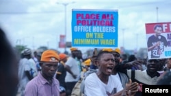 Manifestantes gritam palavras de ordem enquanto participam num protesto ao longo de uma estrada em Lagos.