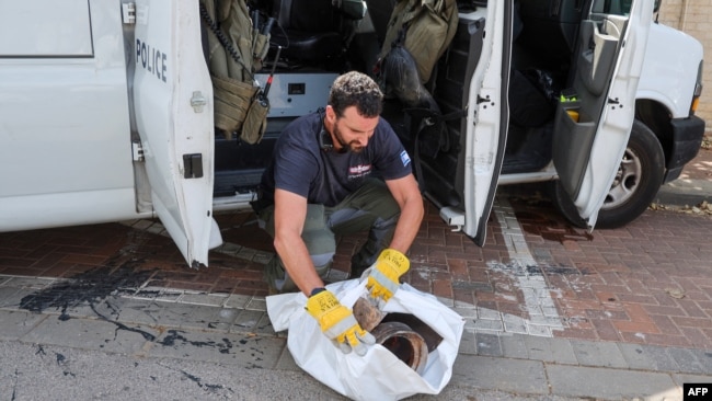 A member of the bomb squad of the Israeli police collects debris after a rocket fired by Palestinian militants struck in the Israeli city of Herzliya on May 26, 2024.