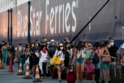 Passengers wait to board a ship bound to Greek Aegean islands at the port of Piraeus, near Athens, Greece, Aug. 1, 2020. Authorities introduced tougher restrictions this week following an increase in infections.