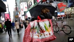 Một người phụ nữ đi qua Quảng trường Thời đại ở New York với những chiếc túi mua sắm trong ngày lễ, ngày 2/12/2015.