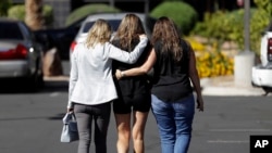 Kris Delarosby, right, and Colleen Anderson, left, hold Charleen Jochim as they walk toward a hospital in search of information about a missing friend, Steven Berger of Minnesota, Oct. 3, 2017, in Las Vegas.