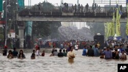 Ribuan warga Jakarta terpaksa mengungsi melalui jalanan yang tergenang banjir, Rabu (16/1). (AP Photo/Achmad Ibrahim)