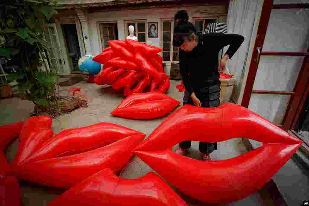 Artist and environmental activist Kong Ning prepares inflatable lip-shaped balloons with a theme — &quot;Kiss the Earth&quot; — in support on Earth Day in Beijing, China.