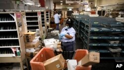 FILE - A United States Postal Service carrier sorts mail to be delivered before she sets out on her route in Philadelphia, Pennsylvania, May 6, 2020. 