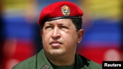 FILE - Venezuelan President Hugo Chavez wears an army uniform and the red beret of his parachute regiment while he attends a military parade in Caracas, April 13, 2005.
