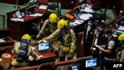 Members of the fire brigade conduct decontamination work in the main chamber of the Legislative Council after pan-democrat lawmakers hurled an odorous liquid during the third reading of the national anthem bill in Hong Kong on June 4, 2020, ahead of…