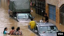 Warga bersusah payah melintasi banjir di pusat kota Hat Yai, Provinsi Songkhla, Thailand.