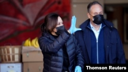 U.S. Vice President-elect Kamala Harris waves near her husband, Doug Emhoff, as they volunteer at Martha's Table on Martin Luther King Jr. Day in Washington, Jan. 18, 2021. 