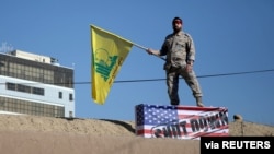An Iranian guard holds a Hezbollah flag during a funeral procession and burial for Iranian Major-General Qassem Soleimani, in Kerman, Iran, Jan. 7, 2020. 