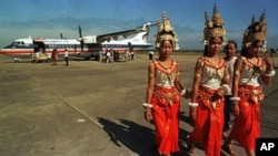 Cambodian dancers walk past a Thai airline, Bangkok Airways plane at Siem Reap's airport in northern Cambodia.