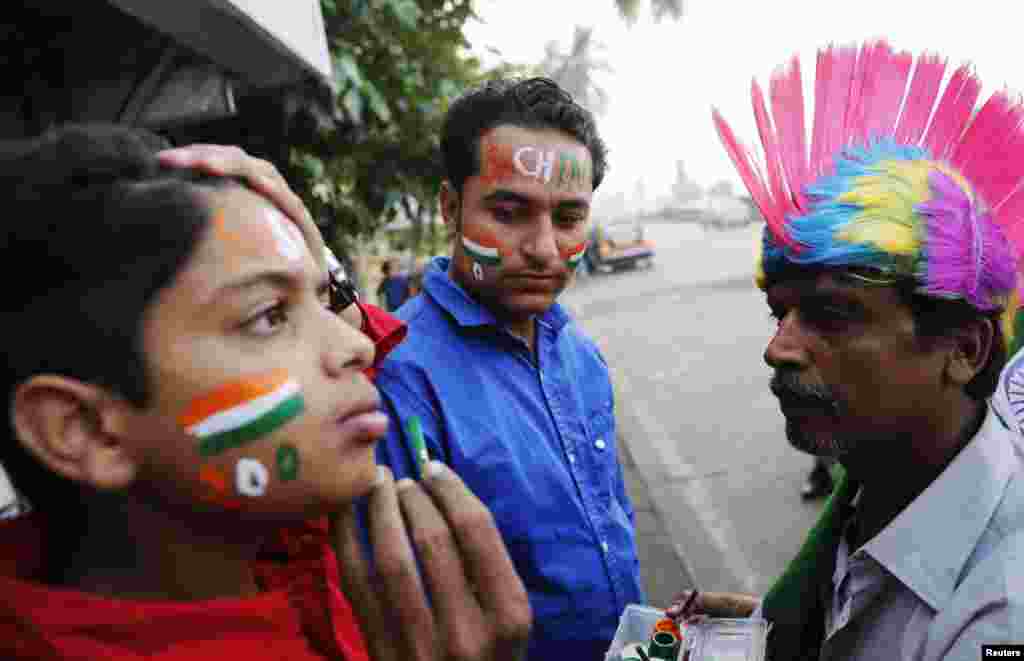 Cricket fans get their faces painted before a match outside a stadium in Mumbai, Nov. 14, 2013.