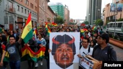 People carry a placard depicting Bolivian President Evo Morales with red horns during a protest march in La Paz, Bolivia, Oct. 26, 2019.