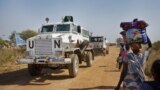 FILE: A United Nations armored vehicle travelling in convoy with a truck passes displaced people walking towards the U.N. camp where they have sought shelter in Malakal, South Sudan. Taken Monday, Dec. 30, 2013.