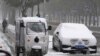 Seorang petugas pengantaran dengan motornya bergerak melewati mobil yang berselimut salju di di Beijing, China, pada 7 November 2021. (Foto: AP/Ng Han Guan)