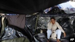 Una mujer salvadoreña espera a saber si la mayor parte de los migrantes deciden trasladarse del campamento en que se encuentran tras una invitación del gobierno municipal para ir a un nuevo refugio en Tijuana, México.