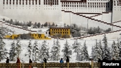 Orang-orang melintasi pepohonan yang diselimuti salju di luar Istana Potala, Lhasa, Daerah Otonomi Tibet, China, 19 Desember 2018 (foto: Reuters/Stringer)