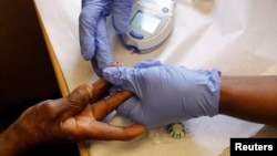 FILE - A patient's finger is pricked for a blood test.