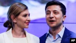 Presiden terpilih Ukraina Volodymyr Zelenskiy (kanan) dan istrinya Olena Zelenska menyalami pendukungnya di ibu kota Kyiv Minggu (21/4).