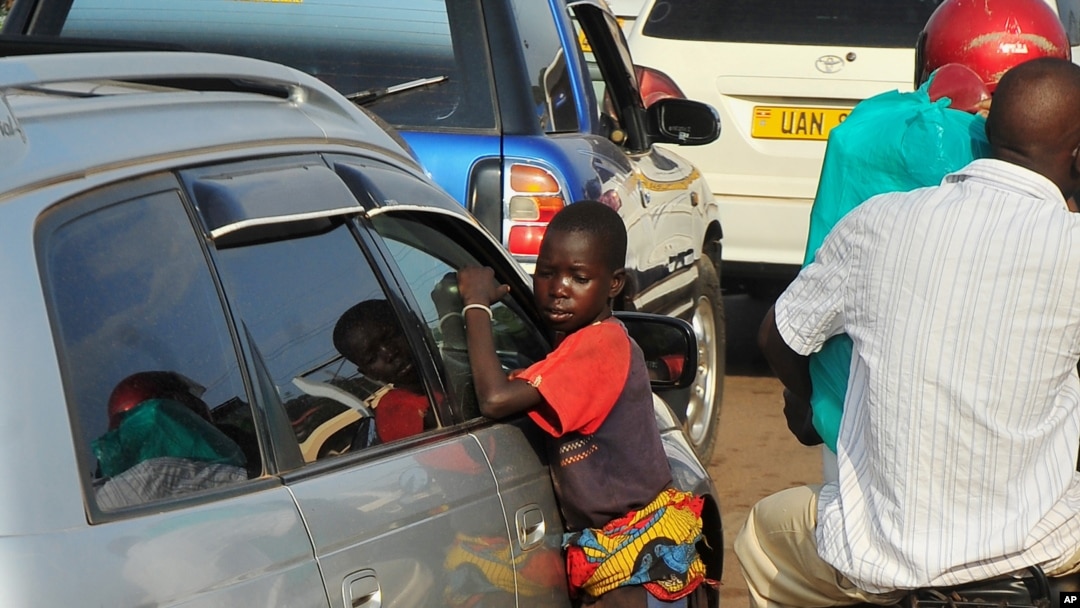 FILE - A Ugandan street child begs as traffic passes by, in Kampala, July 17, 2014.