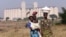 Malawian women walk past empty grain silos in the capital Lilongwe, (File photo).
