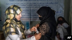 FILE -An Afghan woman, right, is checked by a nutritionist at a clinic run by the World Food Program in Kabul, Afghanistan, Jan. 26, 2023. Many female doctors have left Afghanistan since the Taliban returned to power in August 2021.