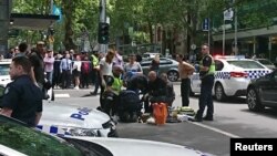 Members of the public watch as police and emergency services attend to an injured person after a car hit pedestrians in central Melbourne, Australia, Jan. 20, 2017.