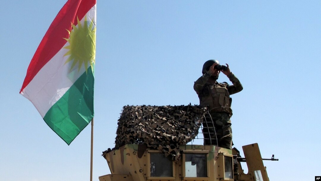 FILE - A member of the Kurdish security forces scans the horizon in Kirkuk, Iraq, from atop a military vehicle flying a flag of the Kurdistan Regional Government, June 14, 2014.