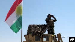 FILE - A member of the Kurdish security forces scans the horizon in Kirkuk, Iraq, from atop a military vehicle flying a flag of the Kurdistan Regional Government, June 14, 2014.