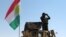 FILE - A member of the Kurdish security forces scans the horizon in Kirkuk, Iraq, from atop a military vehicle flying a flag of the Kurdistan Regional Government, June 14, 2014.