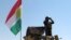 FILE - A member of the Kurdish security forces scans the horizon in Kirkuk, Iraq, from atop a military vehicle flying a flag of the Kurdistan Regional Government, June 14, 2014.
