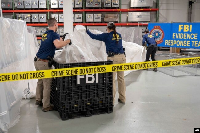 En esta imagen facilitada por el FBI, agentes asignados a un equipo especial manipulan el jueves 9 de febrero de 2023, en el laboratorio de la agencia, los materiales recuperados de un globo chino supuestamente espía que fue derribado en aguas frente a la costa de Carolina del Sur. (FBI vía AP)
