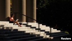 FILE - A student uses her laptop computer on the steps to Memorial Church at Harvard University in Cambridge, Massachusetts, Sept. 21, 2009. 