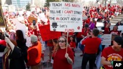 FILE - Amber Malin, a teacher in the Aurora, Colo., public schools system, holds up a placard during a teacher rally in Denver, April 27, 2018.