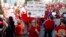 FILE - Amber Malin, a teacher in the Aurora, Colo., public schools system, holds up a placard during a teacher rally in Denver, April 27, 2018.